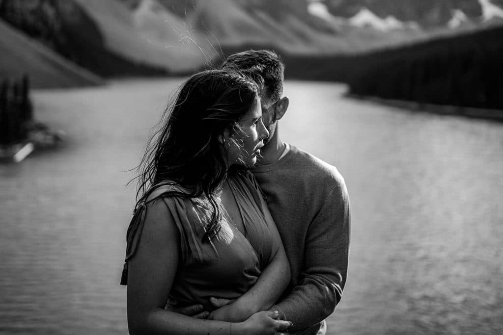 photograph of a couple at Moraine Lake hugging and holding each other during a cold day during the summer in the Canadian Rockies