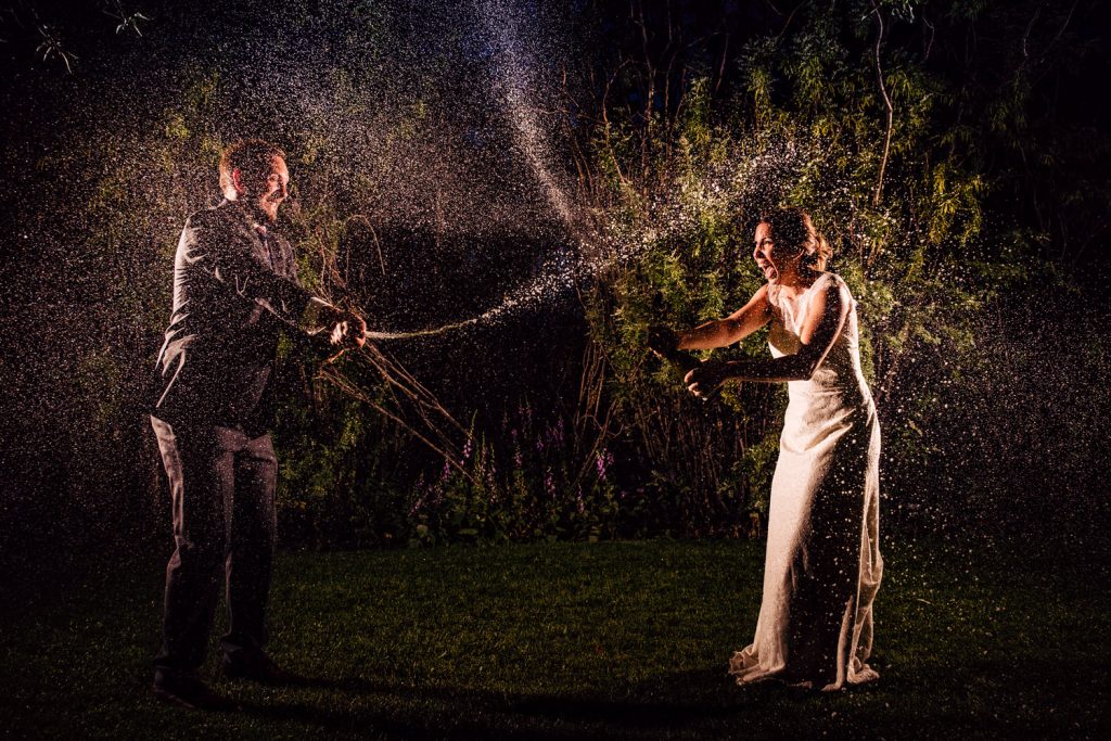 A bride and groom spraying champagne at each other at the Rouge Restaurant in Calgary