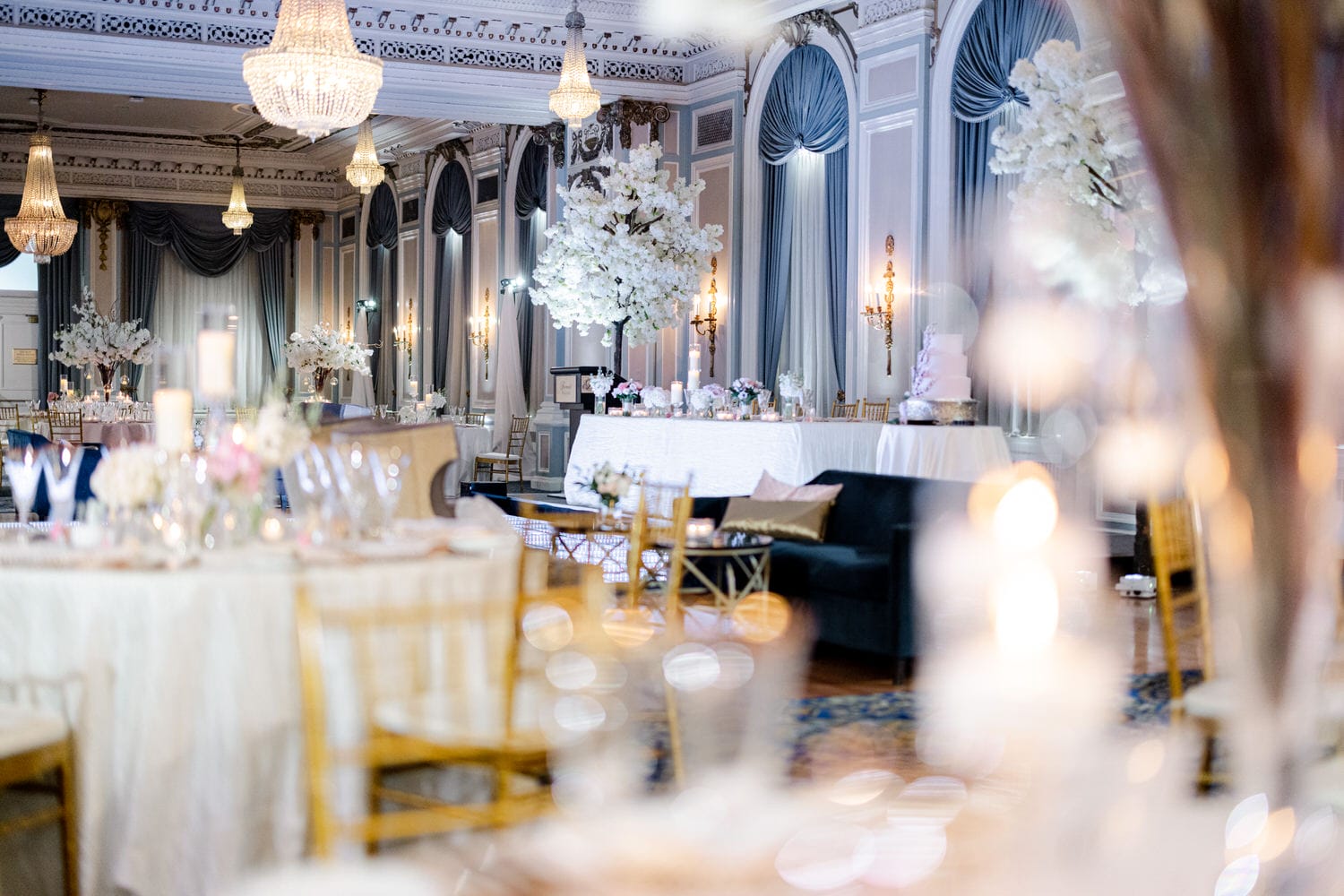 Interior of a beautifully decorated banquet hall with set tables, flowers, and chandeliers, ready for a festive event