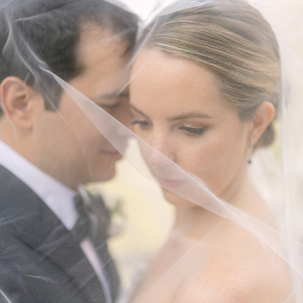 Close-up of a bride and groom sharing a tender moment under the bridal veil.