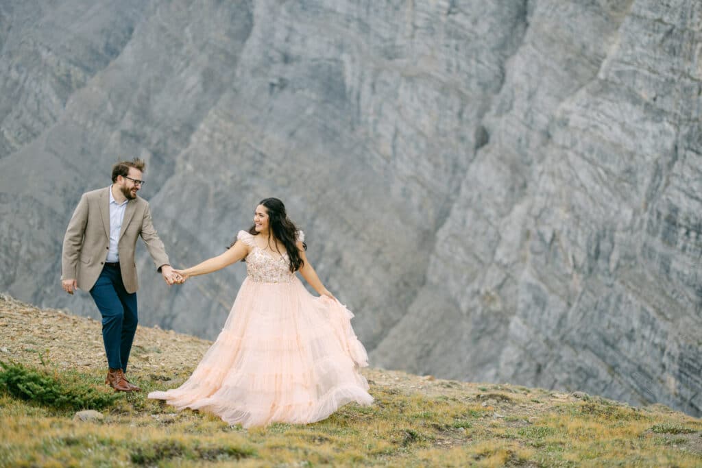 A couple walking hand in hand during their hiking adventure mountain engagement shoot