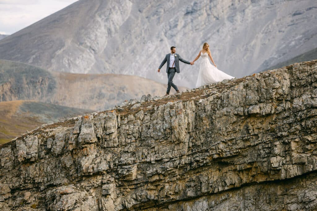 A photograph of a bride and groom walking down a mountain face after getting married during their Alberta Helicopter Elopement