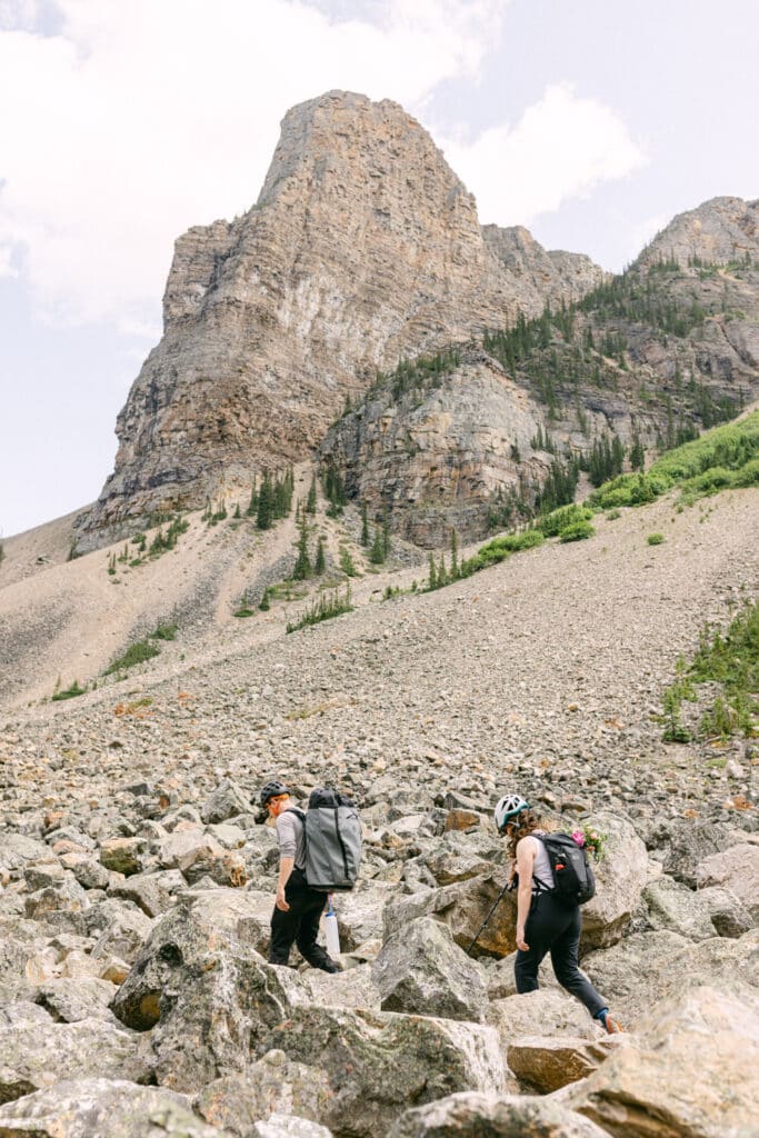 groom and bride are hiking with helmets and hiking clothes so that they can scramble up the mountain for their elopement