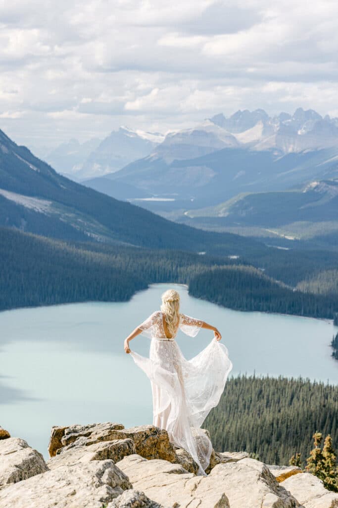 bride letting her dress flow in the wind looking over Peyto Lake Rockies