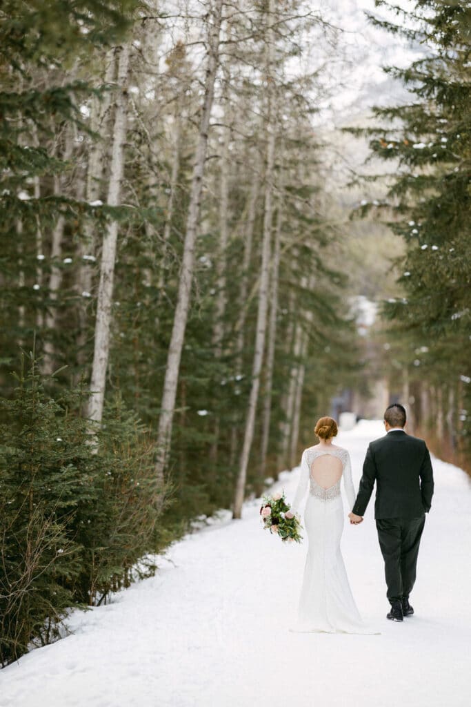 Bride and groom walking in Canmore towards the historic engine bridge.
