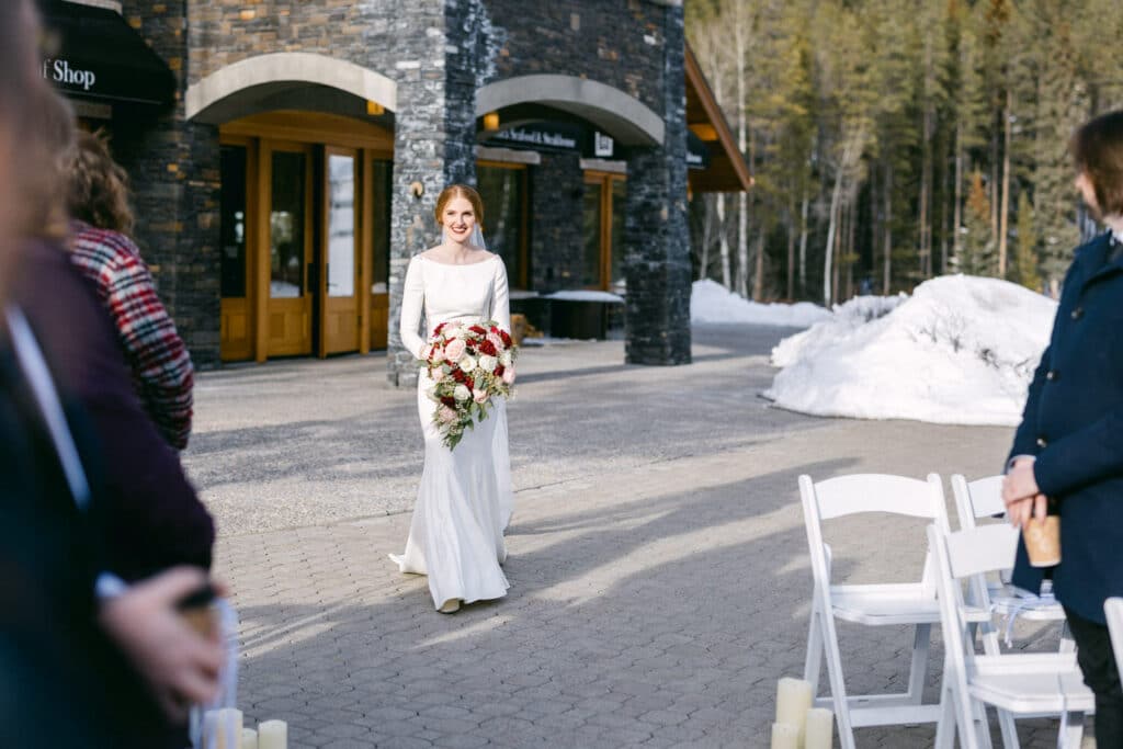 Bride walking down the aisle at Canmore Golf Resort in Canmore towards her future husband