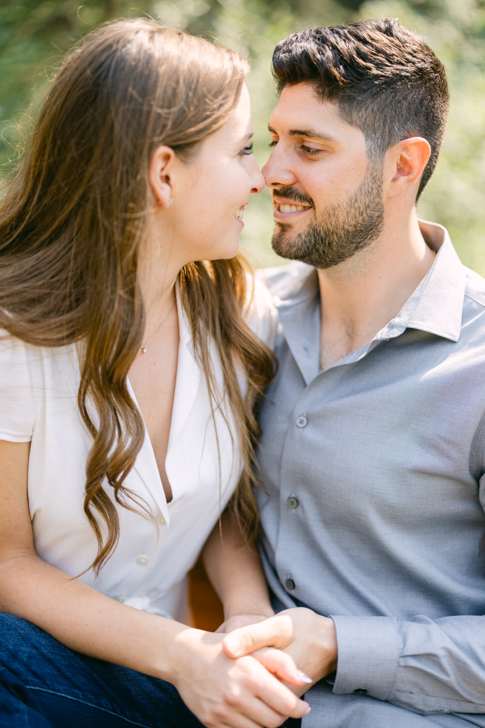 A man and woman holding hands and gazing into each other's eyes with a soft focus background.