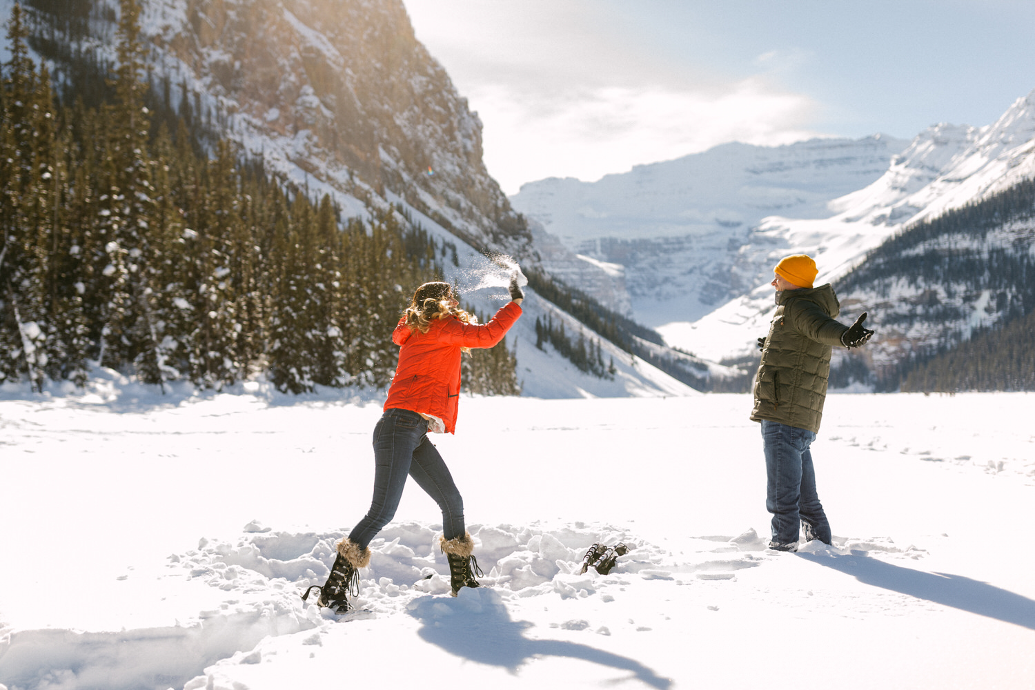 Two people having a snowball fight in a snowy mountain landscape.