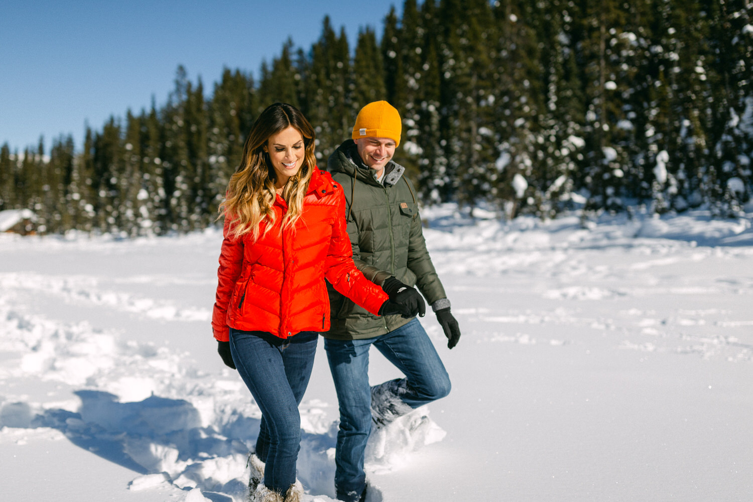 Winter Wanderlust::Two people enjoying a walk in the snow with a forest backdrop