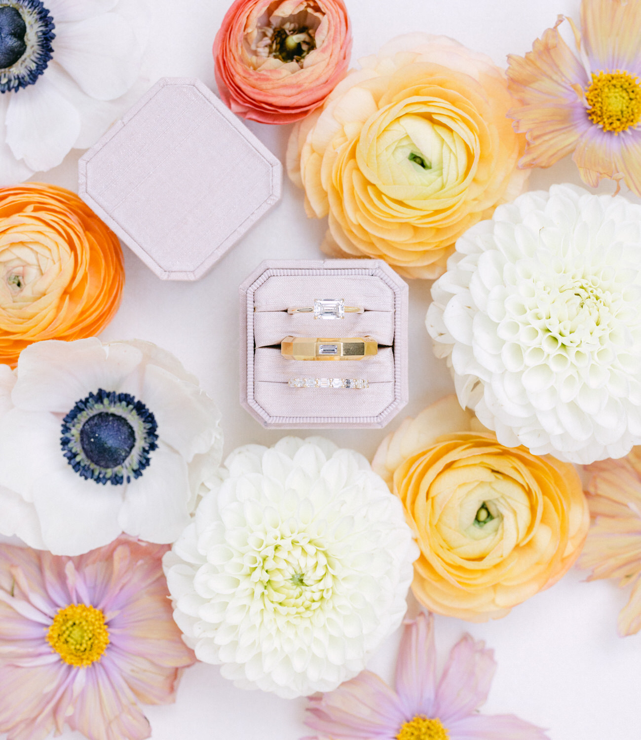 A top view of vibrant flowers with a hexagonal box and a rectangular box containing jewelry, set amidst a bed of colorful blossoms.