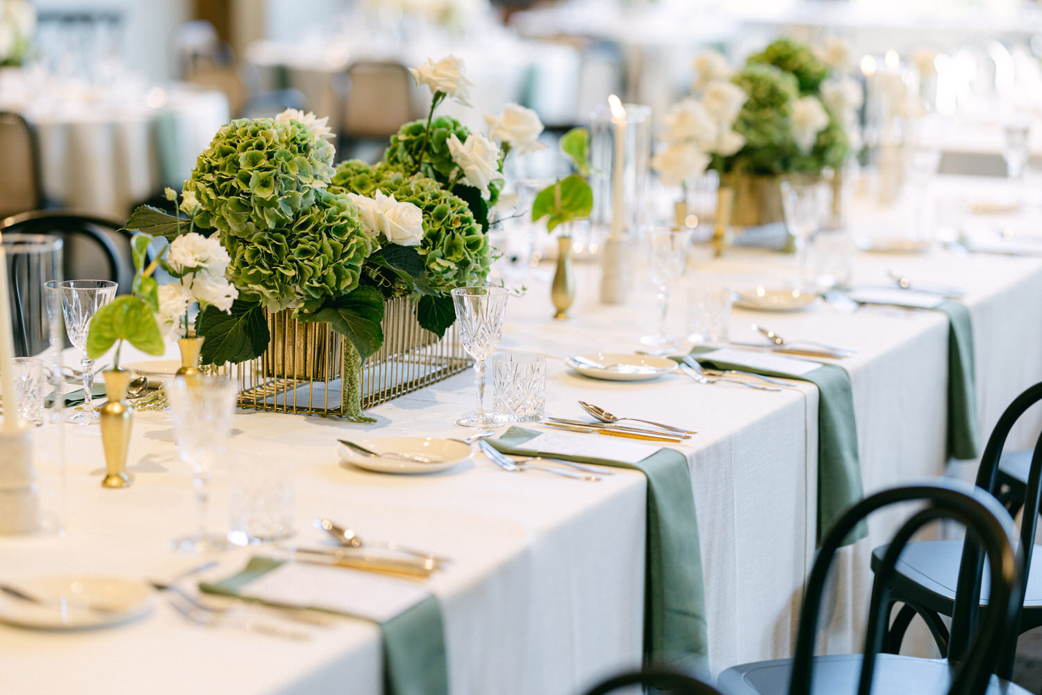 A beautifully arranged wedding table with hydrangea centerpieces, crystal glassware, and fine cutlery.