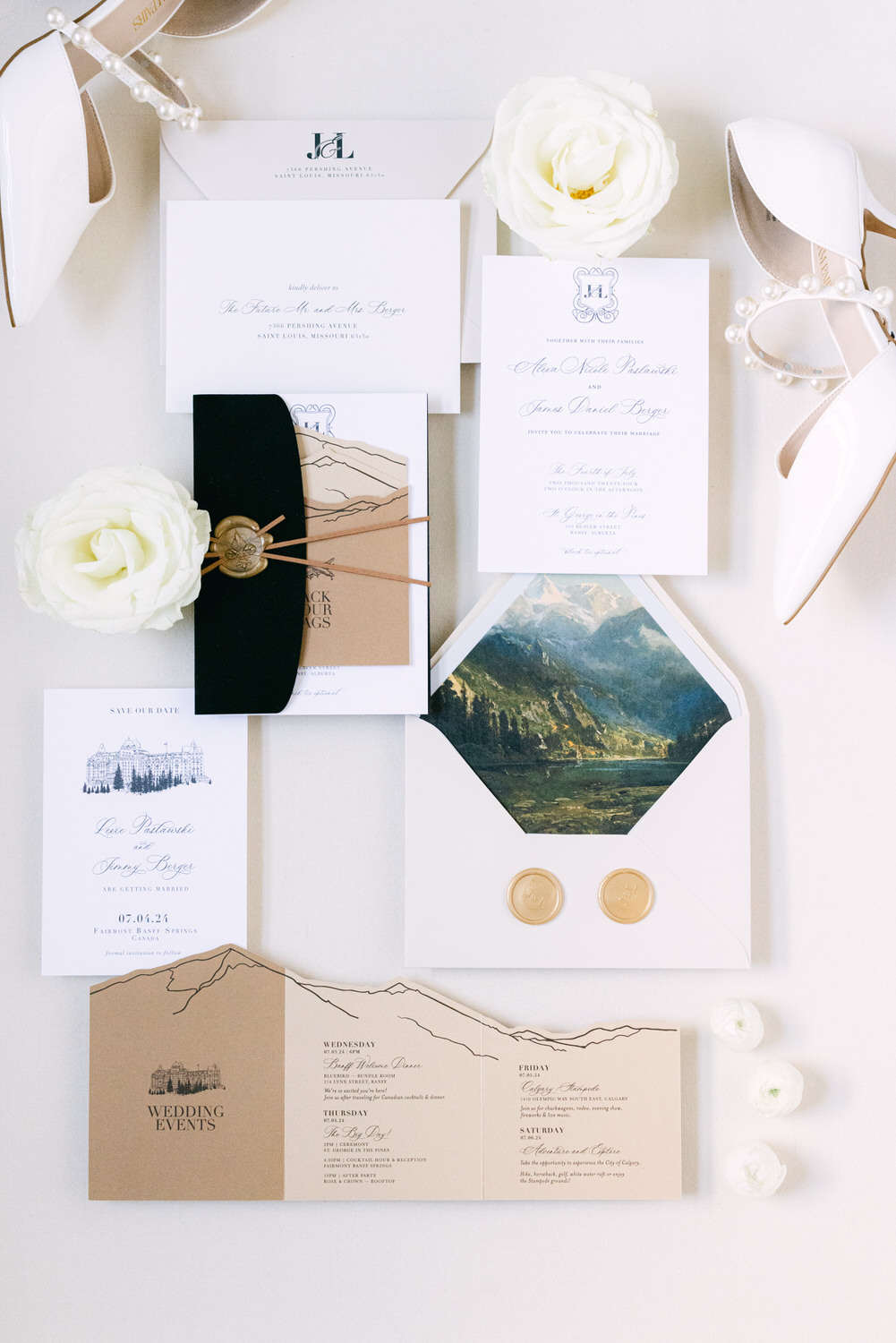 A flat lay of a sophisticated wedding invitation suite with RSVP cards, envelopes with wax seals, a schedule of events, white roses, and bridal shoes.