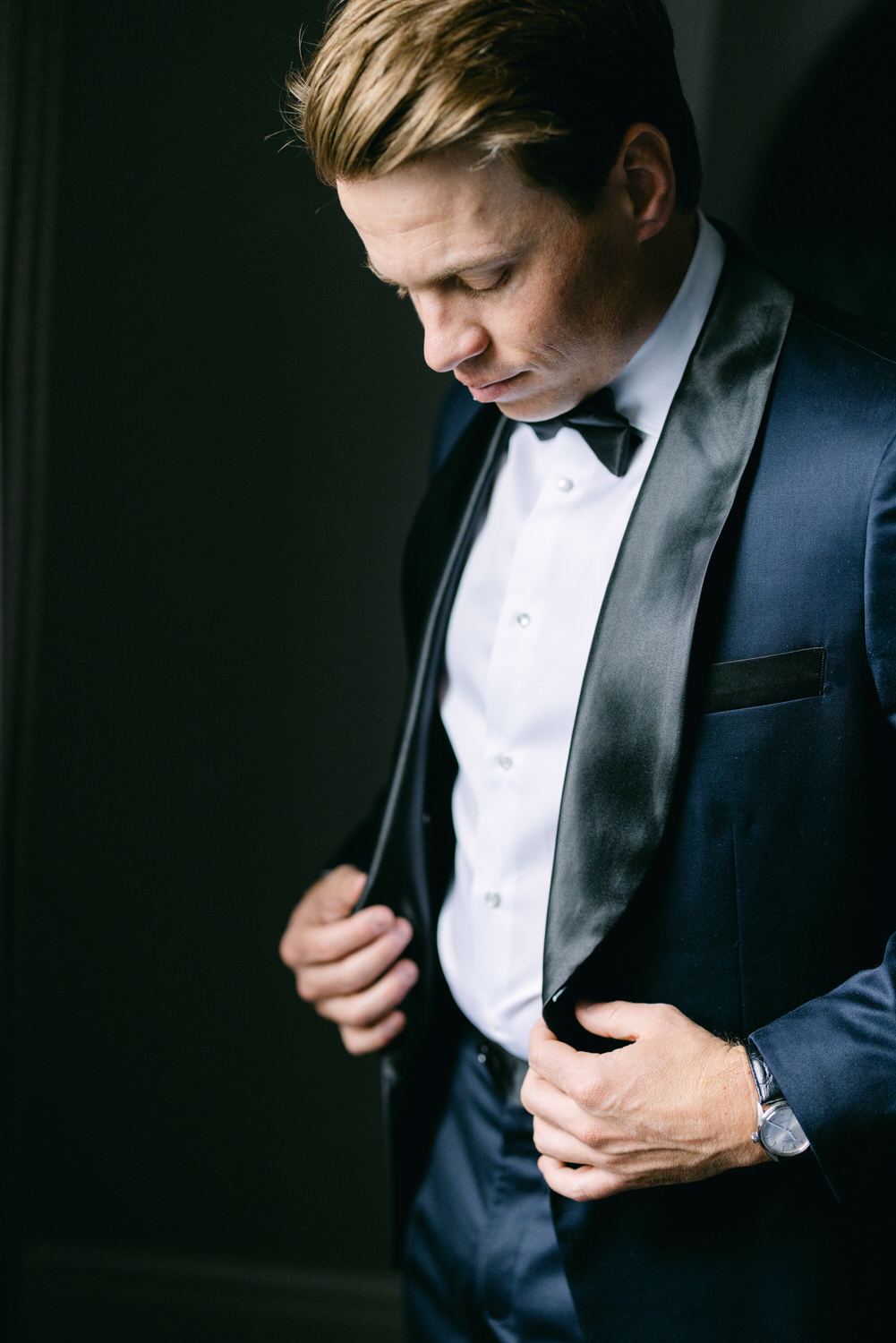 A man in a suit adjusting his jacket with a thoughtful expression.