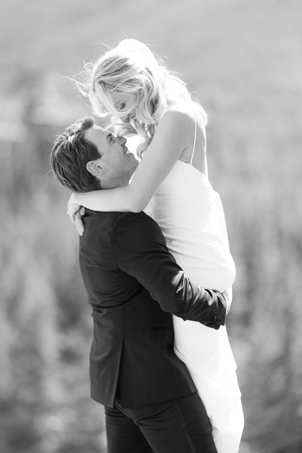 A man lifting and looking affectionately at a woman in a white dress in a monochrome setting.