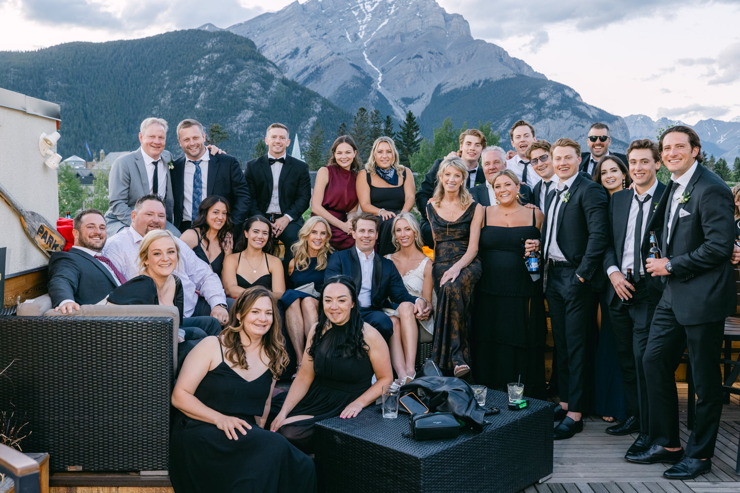 Group of people in formal attire smiling for a photo with mountains in the background