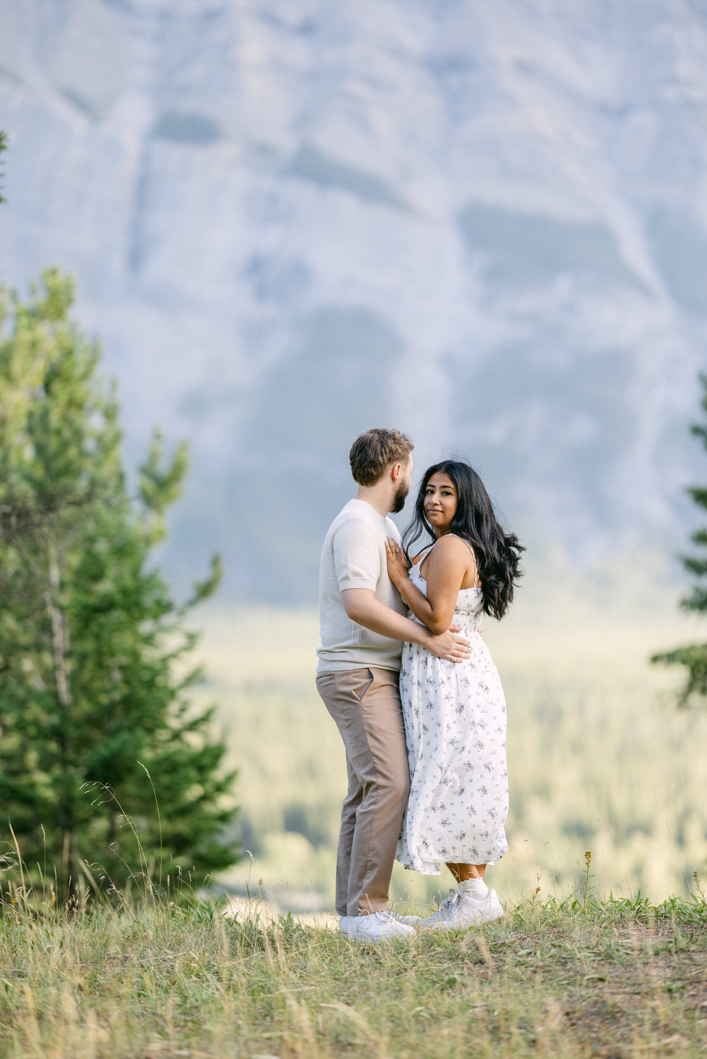 A couple holding each other in a loving embrace in a scenic mountain setting.