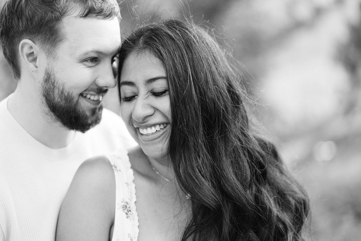 Black and white photo of a smiling couple embracing, showing affection and happiness.