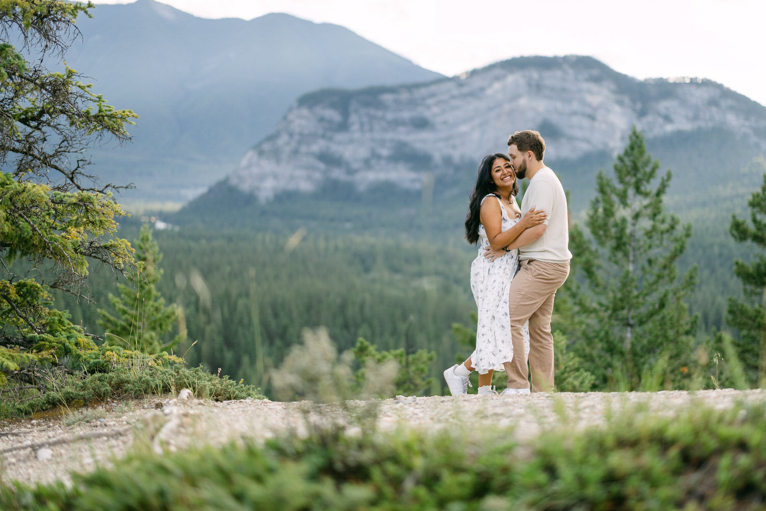 A couple hugging each other with a beautiful mountain landscape in the background.