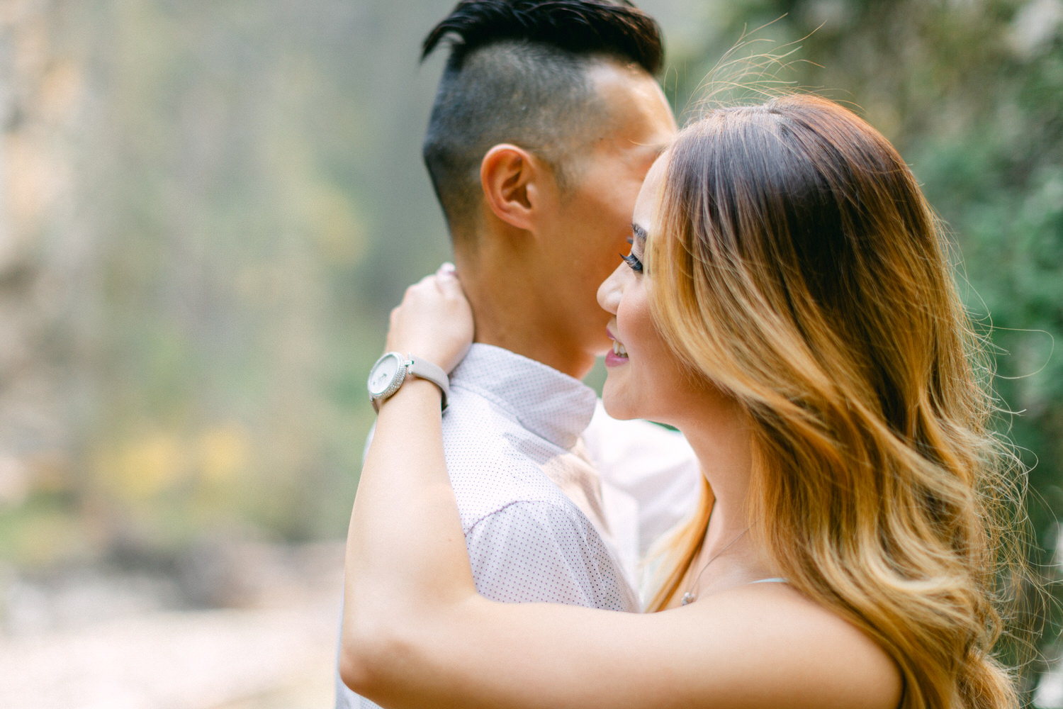 A man and a woman in a loving embrace with a blurred natural background.