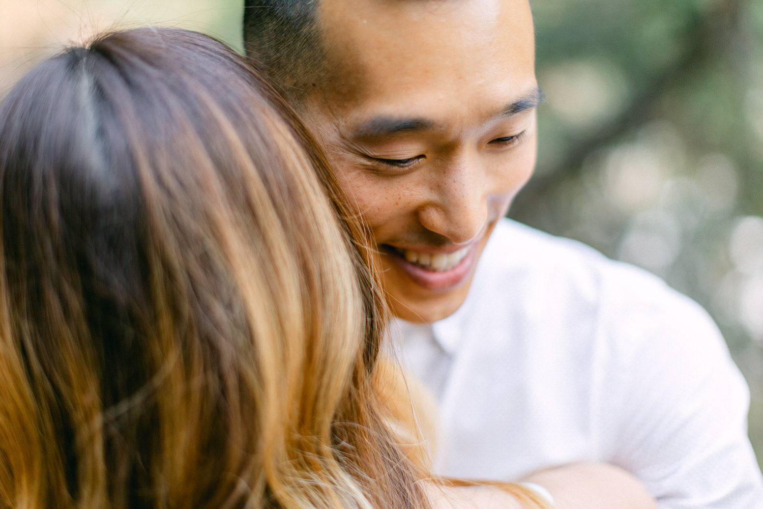 Close-up of a smiling man embracing someone, focus on joyful expression and connection