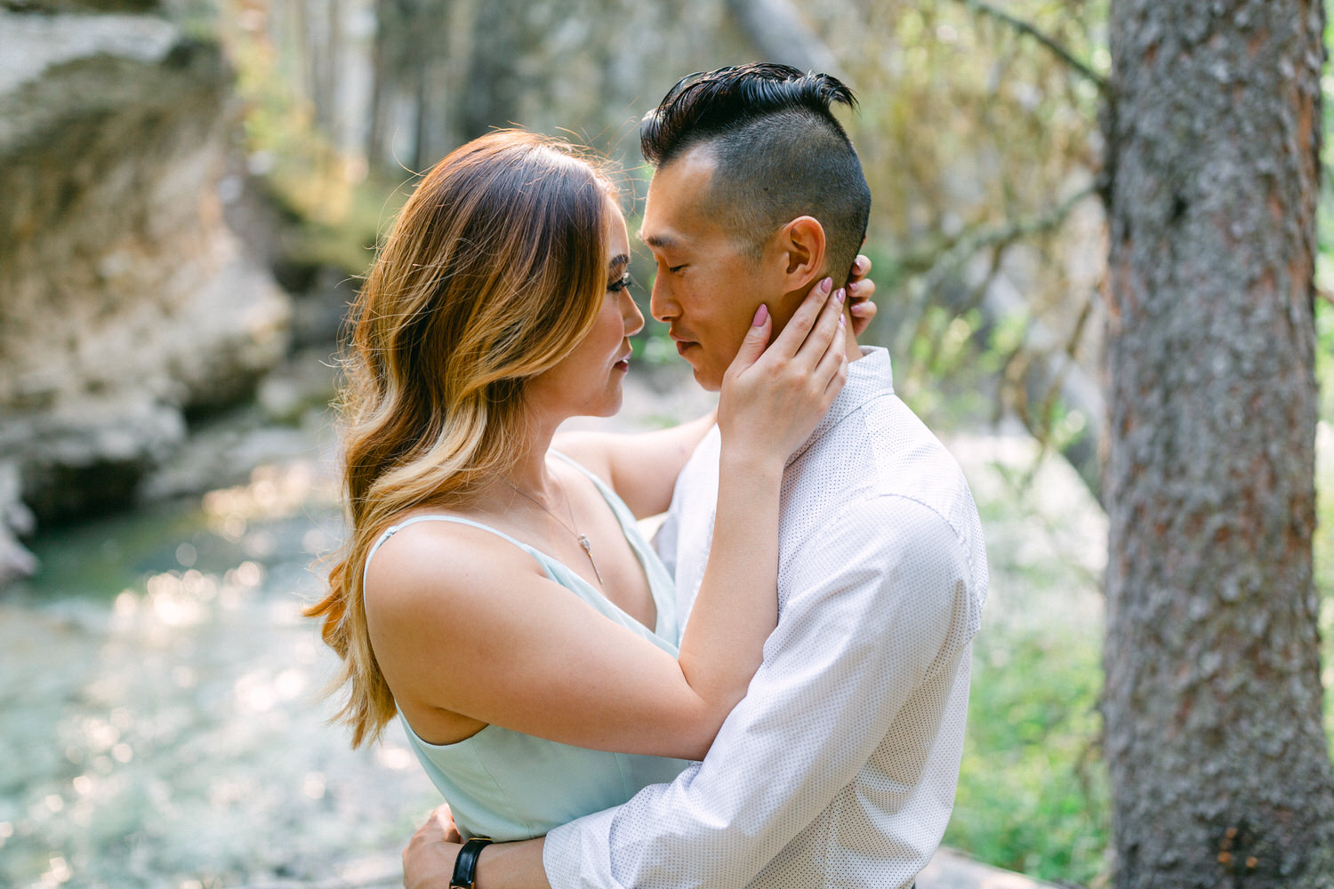 A couple sharing a tender embrace in a serene forest setting.