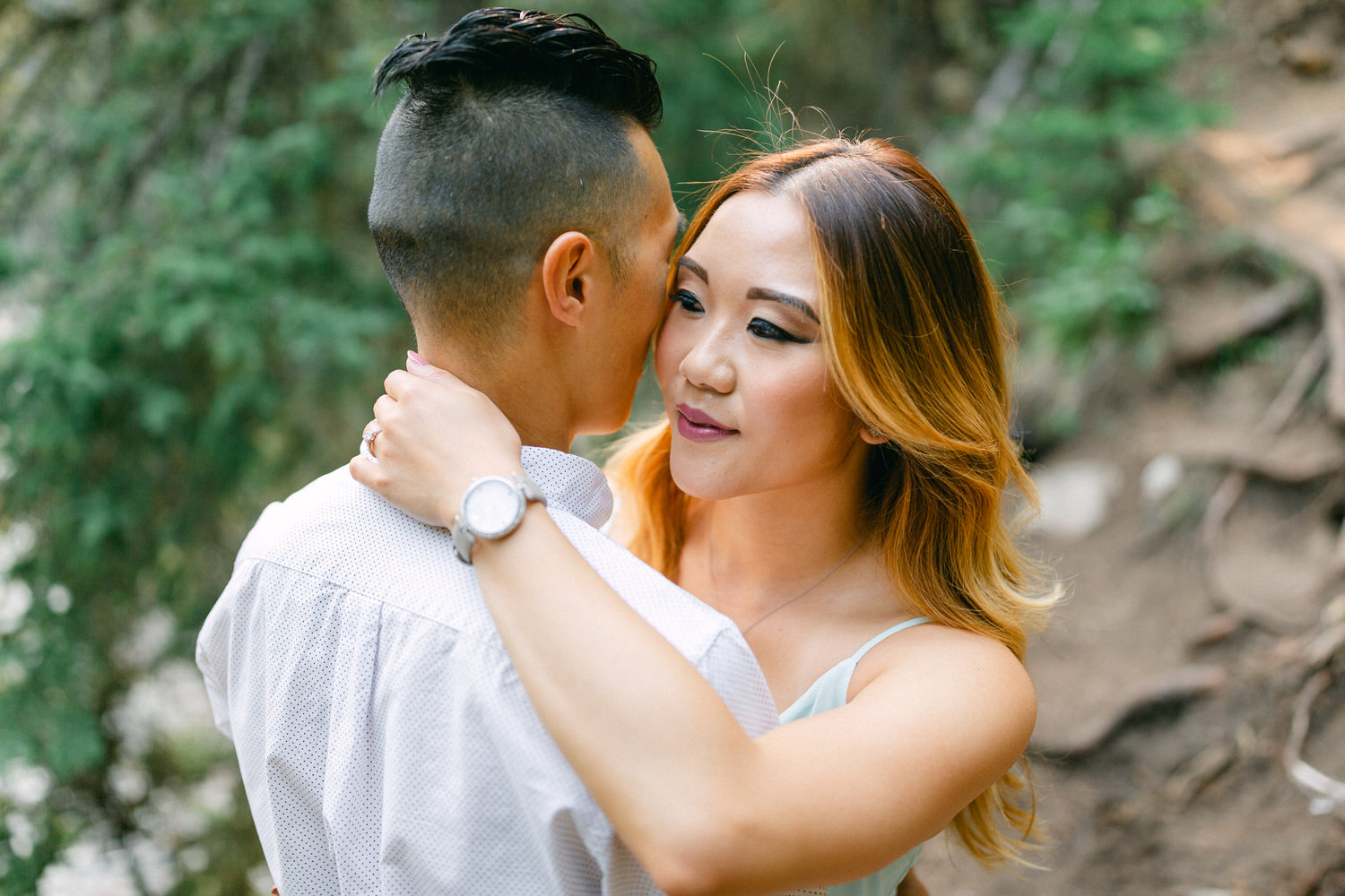 A man and woman embracing and sharing an affectionate moment in a natural outdoor setting.