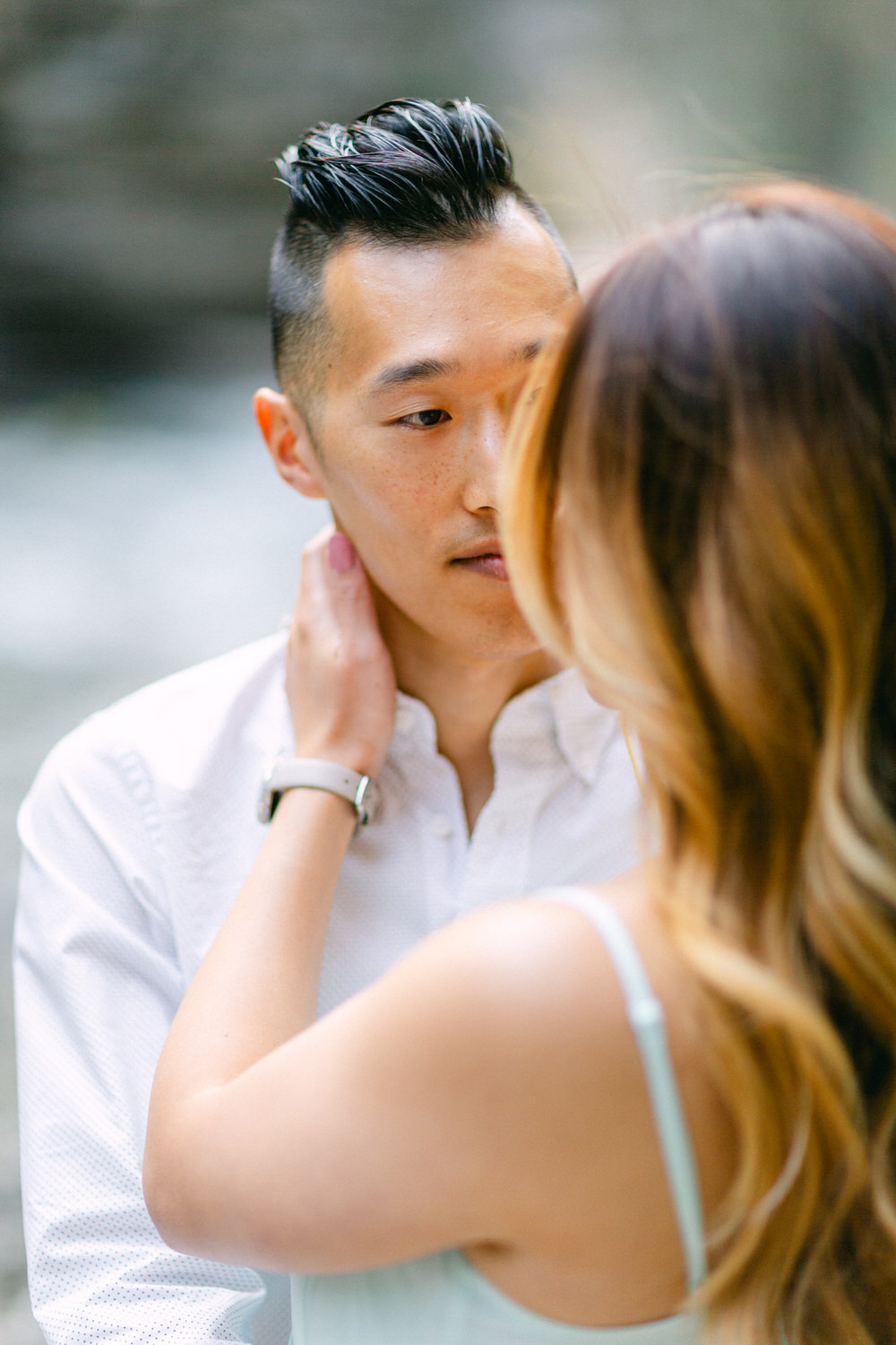 A man being caressed on the face by a woman, both partially visible, evoking a sense of closeness and affection.