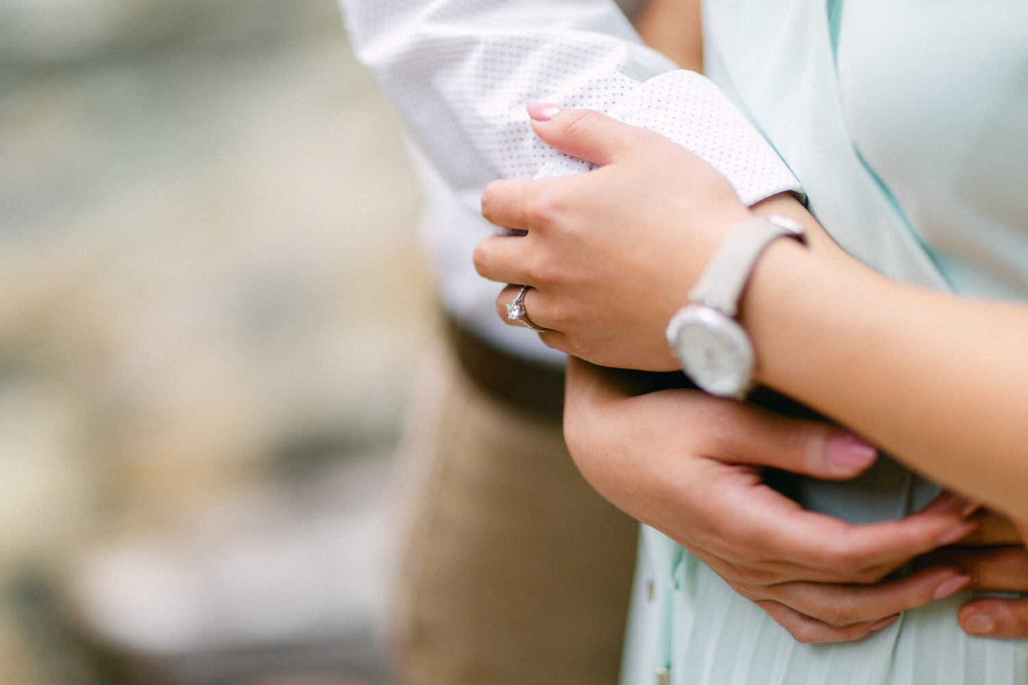 Close-up of a couple's hands embraced with a focus on the engagement ring, signifying a bond of love and promise.