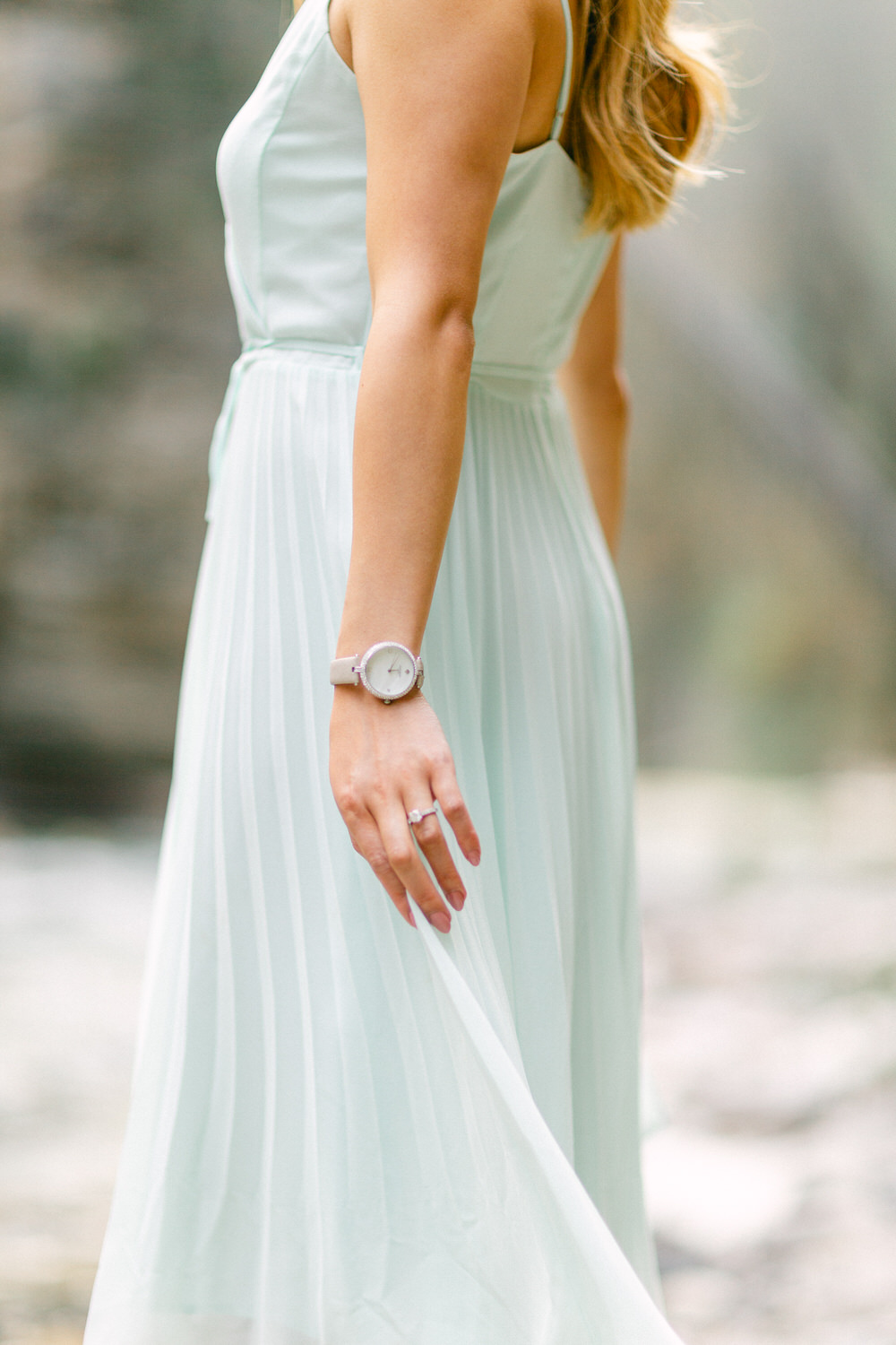 A woman in a pastel dress with focus on her elegant pose and the accessories on her wrist.