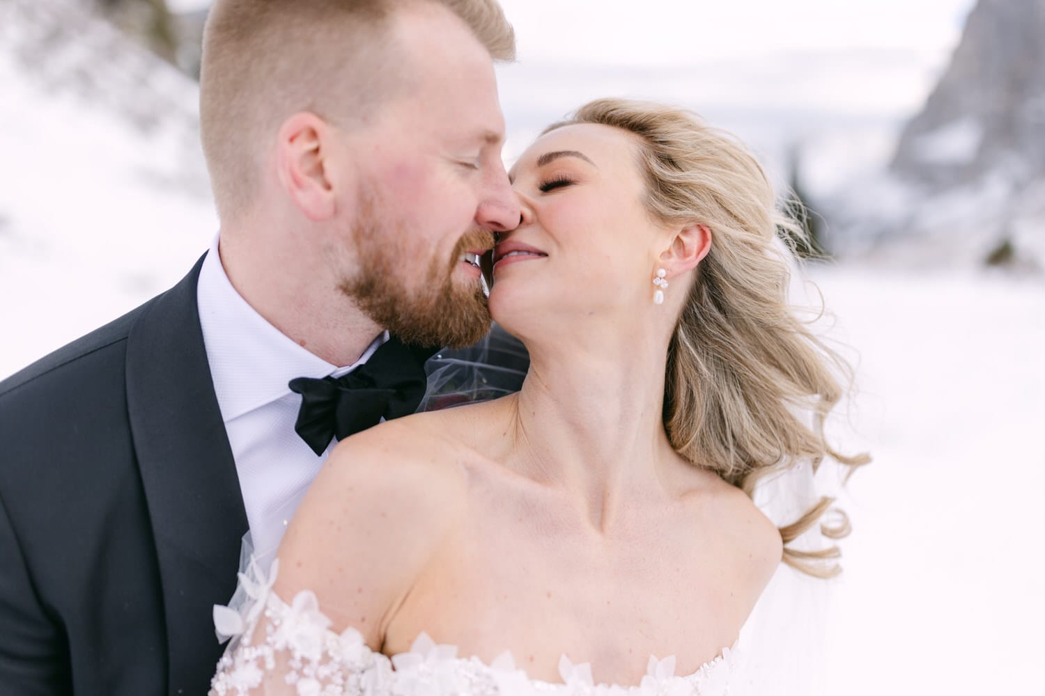 A couple in wedding attire sharing a tender moment in a snowy landscape