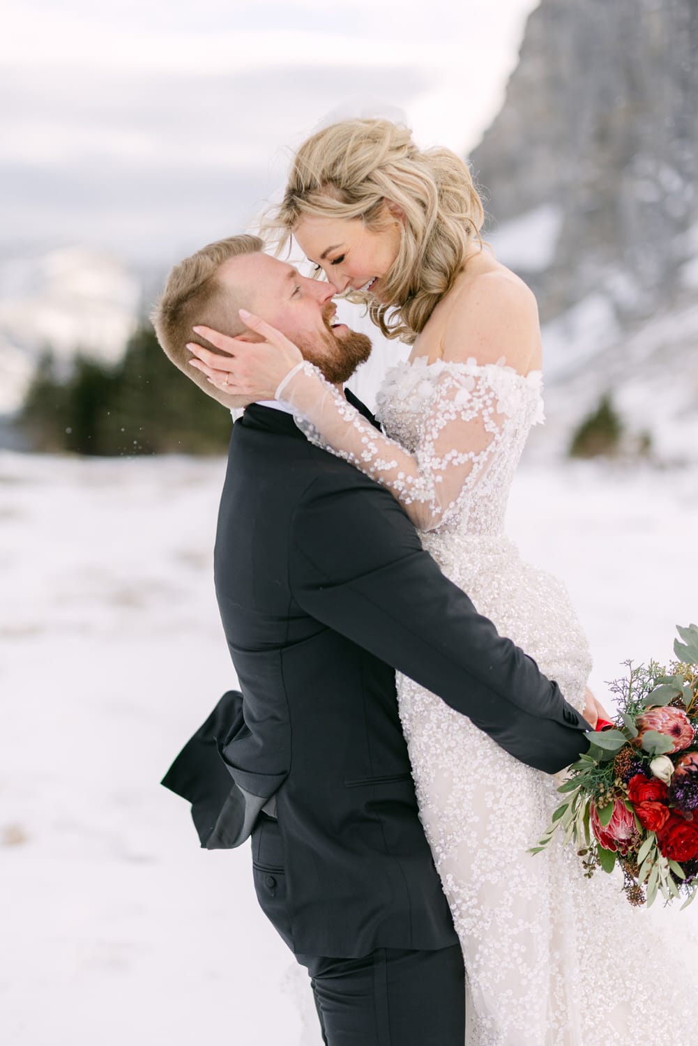 A bride and groom sharing a tender moment in a snowy landscape.