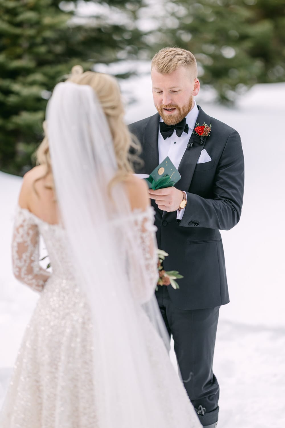 Groom reading vows to bride in snowy setting