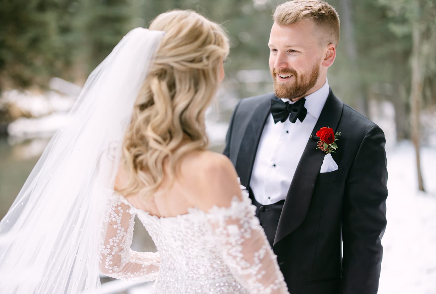 A bride and groom exchanging a loving glance amidst a snowy landscape.