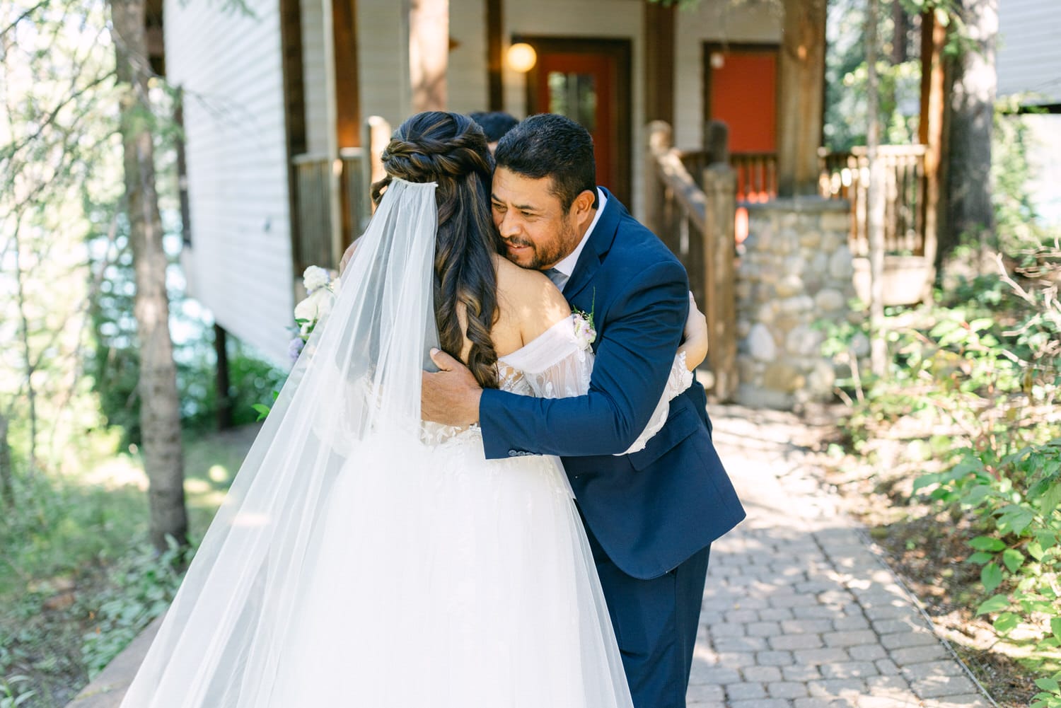 Bride and groom sharing a heartfelt embrace on their wedding day, surrounded by natural scenery.