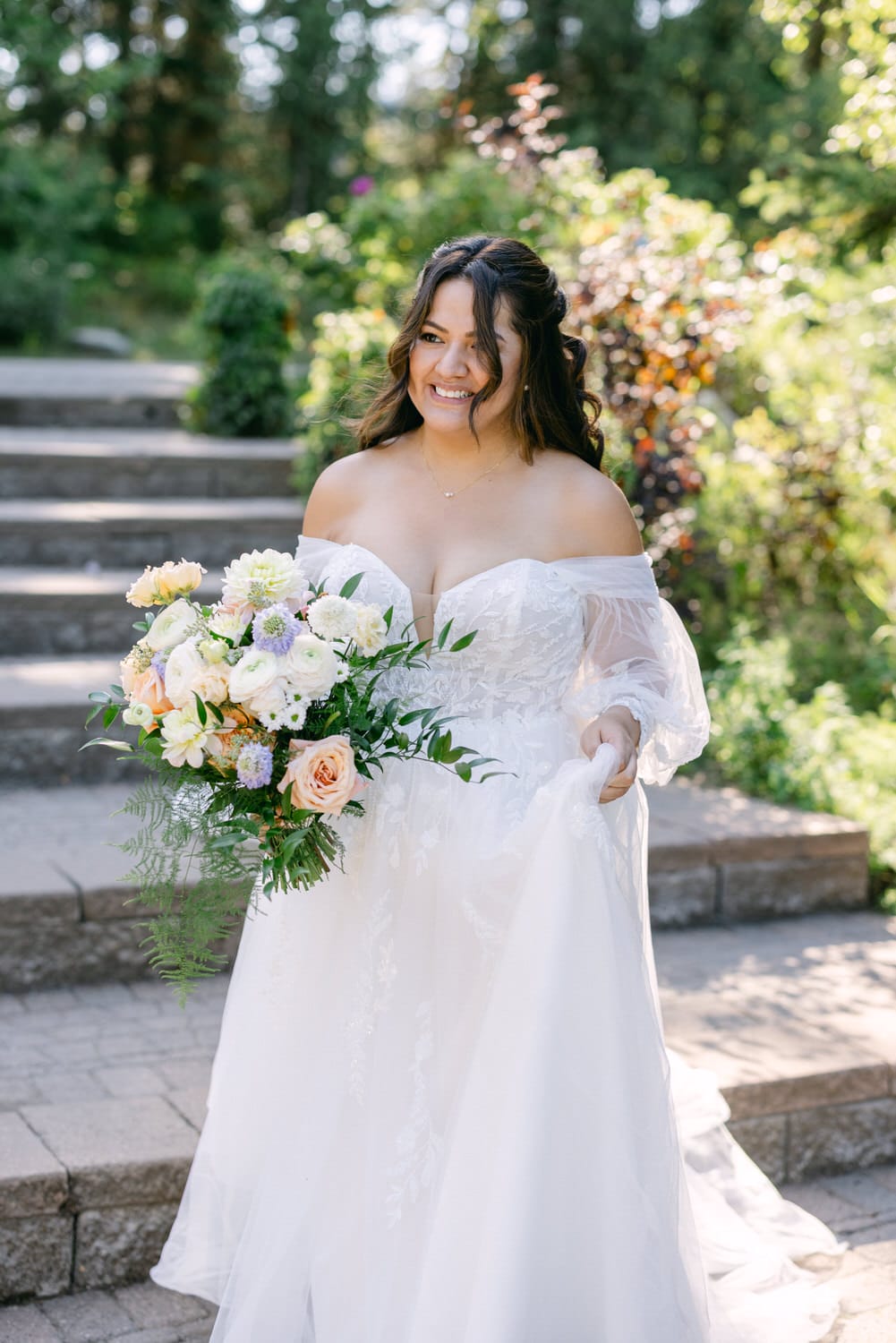 A cheerful bride holding a bouquet and smiling outdoors with greenery in the background