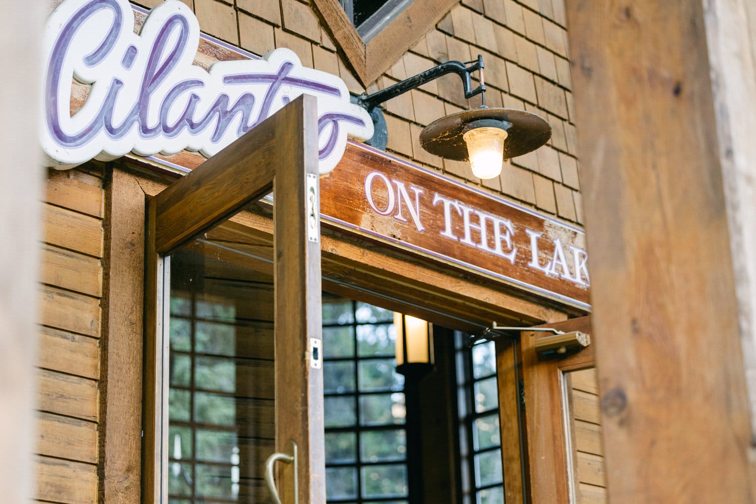 Neon sign above a wooden entrance door with the inscription "Cilantro on the Lake".