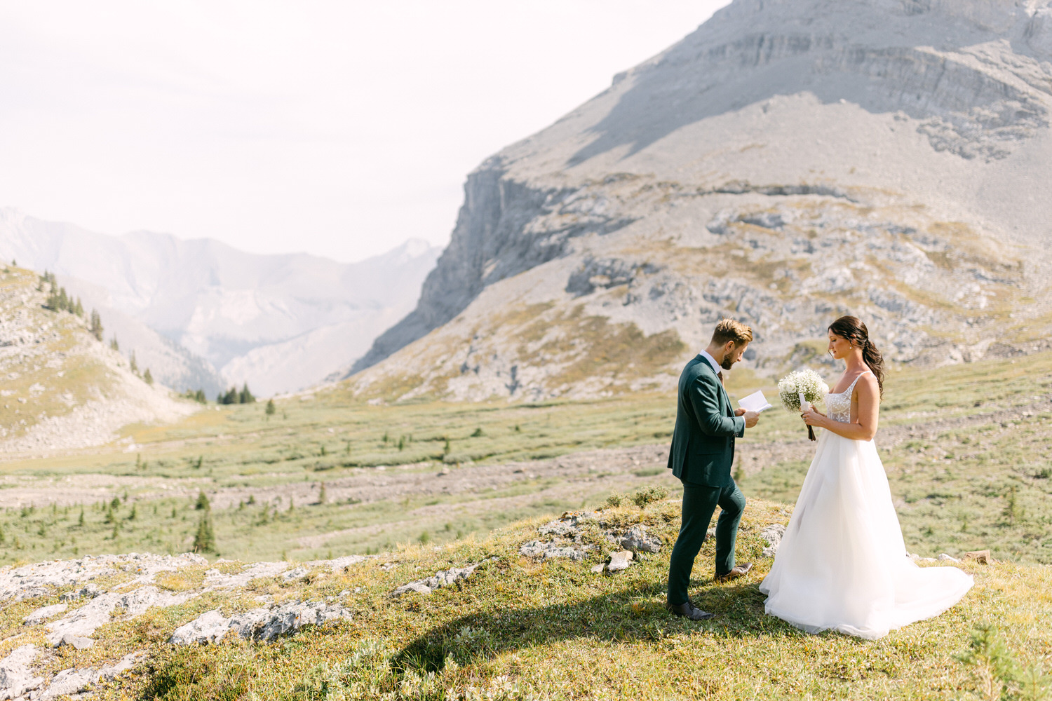 A couple exchanging vows in a picturesque mountain setting, surrounded by lush greenery and majestic peaks.