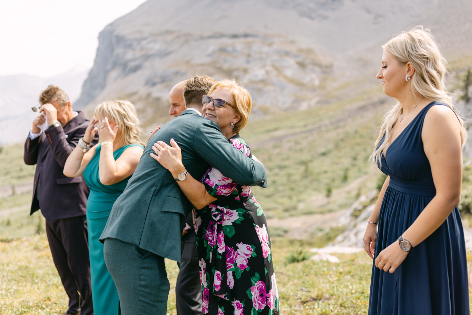 A joyful hug between family members during a heartfelt moment in a scenic outdoor setting.