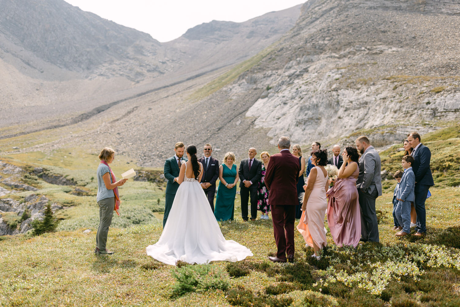 A couple exchanges vows surrounded by family and friends in a beautiful mountainous setting.