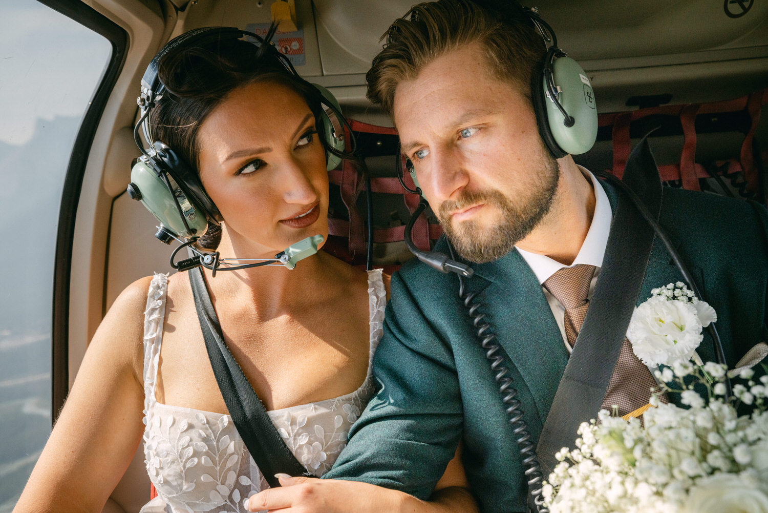 Romantic Helicopter Ride::A couple sharing an intimate moment in a helicopter, both wearing headsets, surrounded by beautiful scenery.