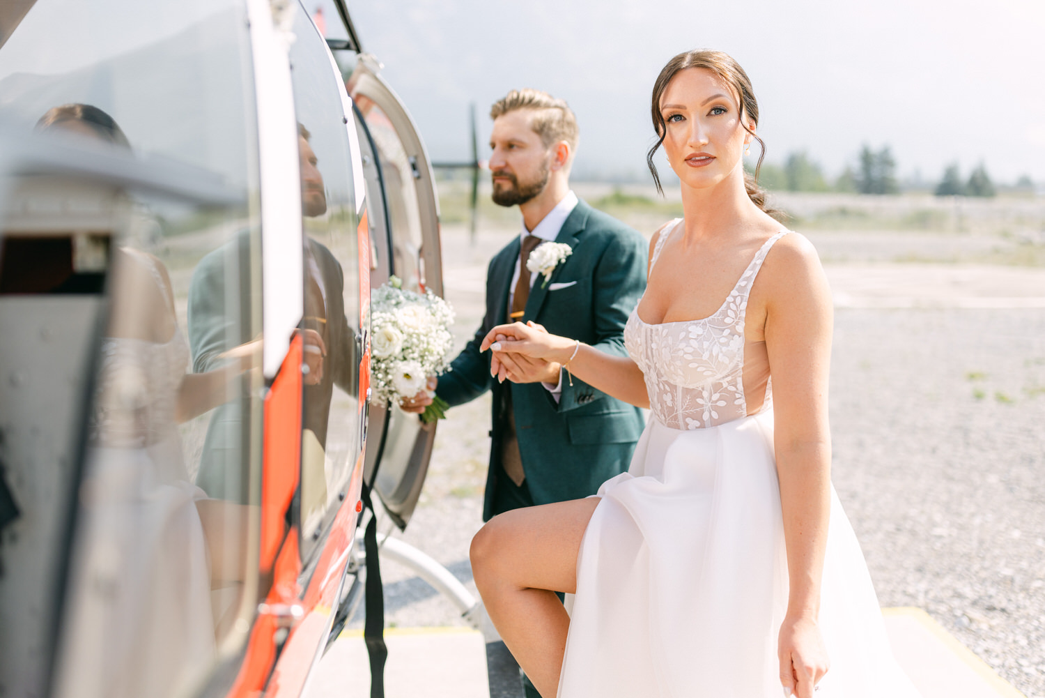 A bride and groom prepare to board a helicopter, with the bride wearing a stunning dress and holding a bouquet, as they embark on their special journey.