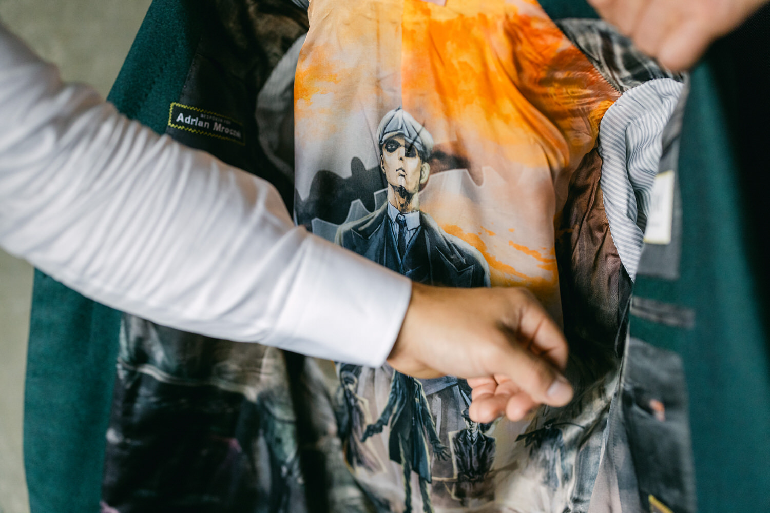 A person revealing the artistic design on the inside lining of a jacket, featuring an illustration of a character against a vibrant background.