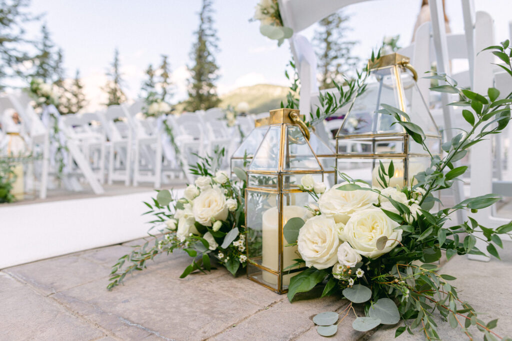 A beautifully arranged setting featuring elegant lanterns and white roses, enhancing a romantic outdoor wedding ceremony atmosphere.