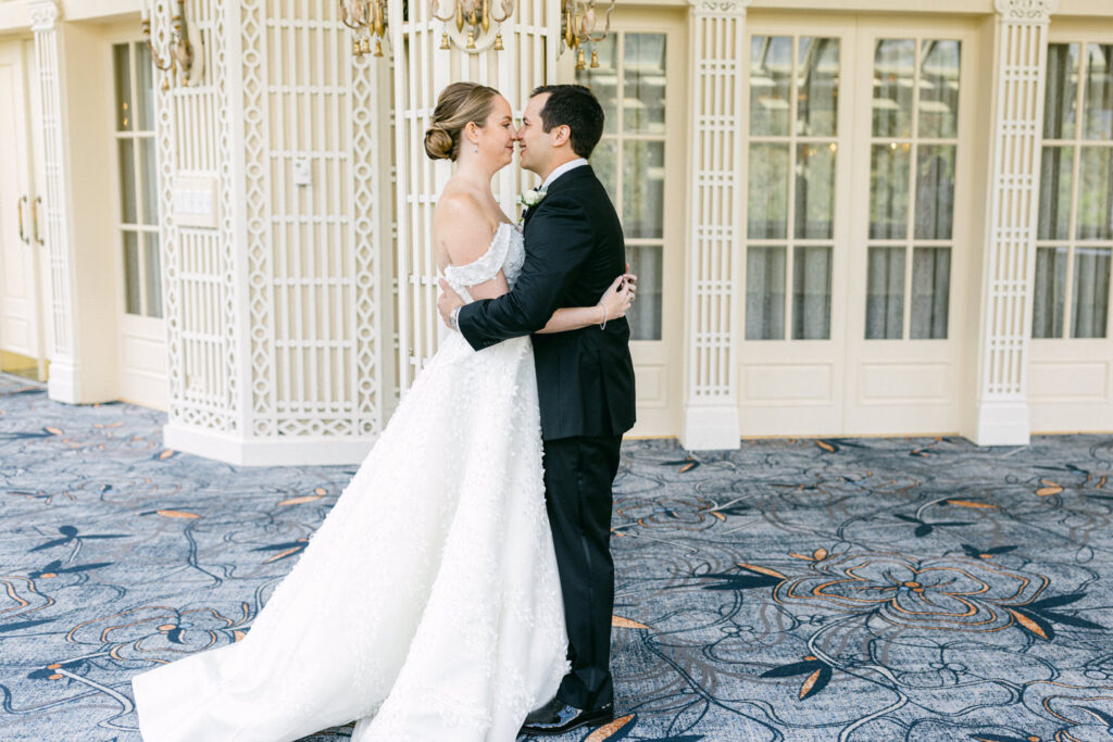 A bride and groom share a tender moment, embracing and leaning in for a kiss in a beautifully decorated venue.