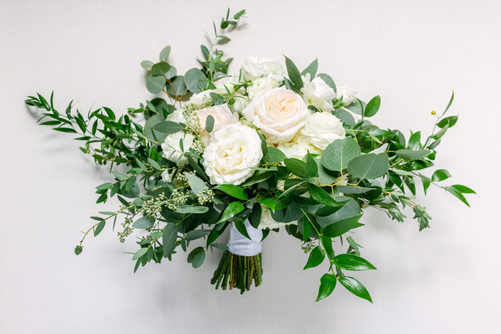 A beautifully arranged bouquet featuring white roses and lush greenery against a soft background.