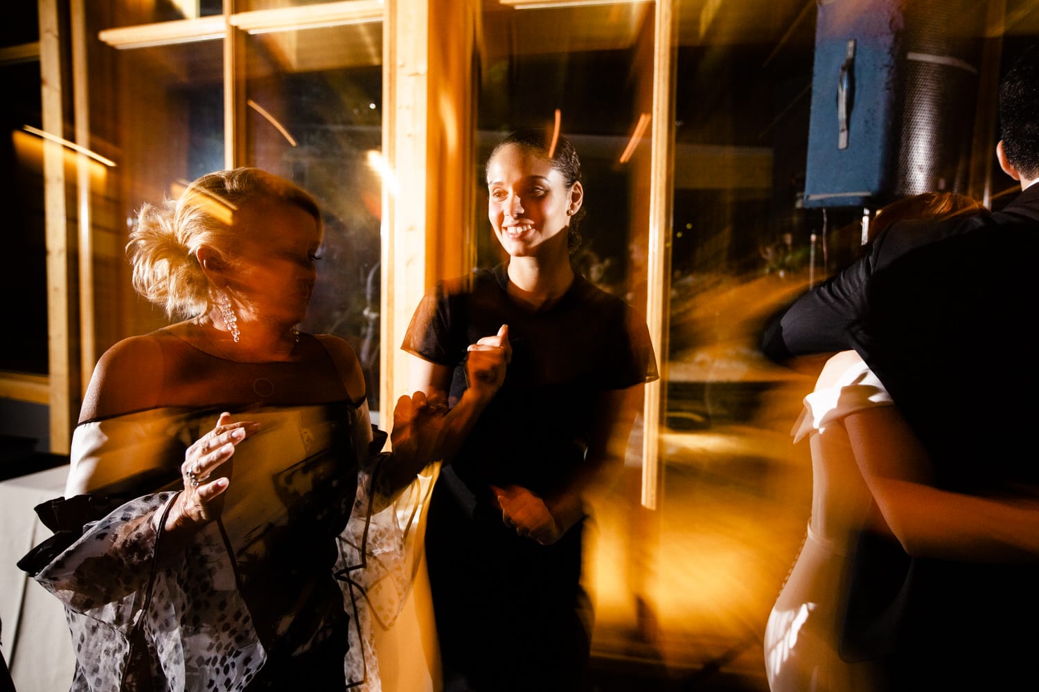 Two women enjoy a lively dance at a celebration, captured with a sense of movement and warmth.