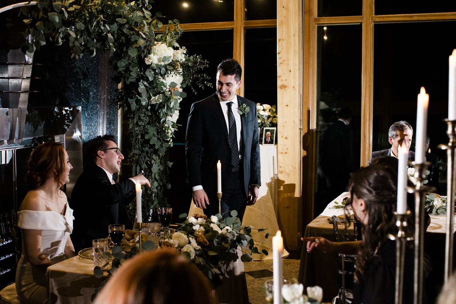 Guests enjoy a heartfelt moment during a wedding reception, surrounded by florals and candlelight.