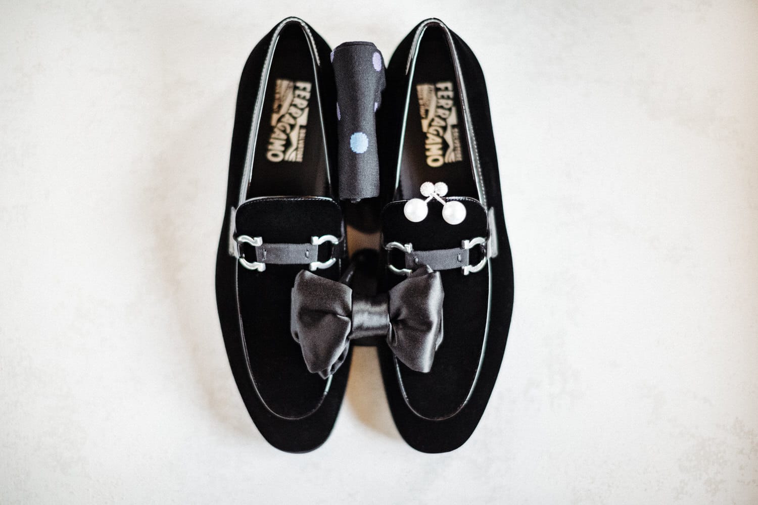 Elegant black velvet loafers featuring a satin bow and decorative accents on a light background.