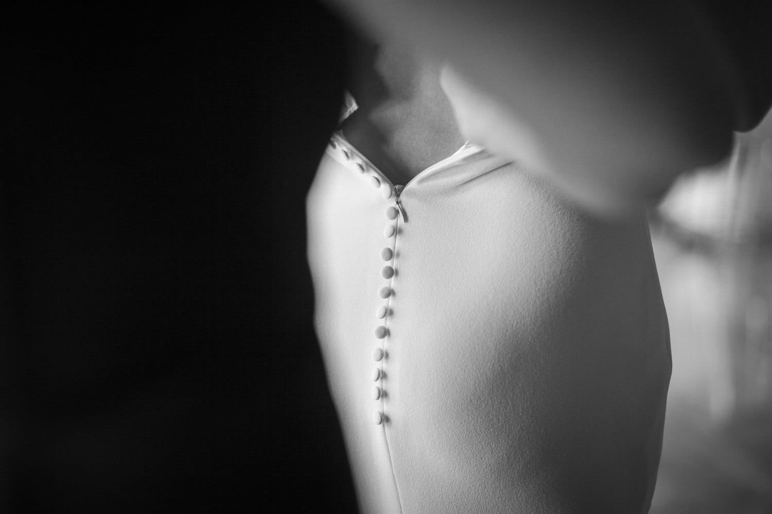 Close-up of a white garment with decorative buttons, set against a dark background.