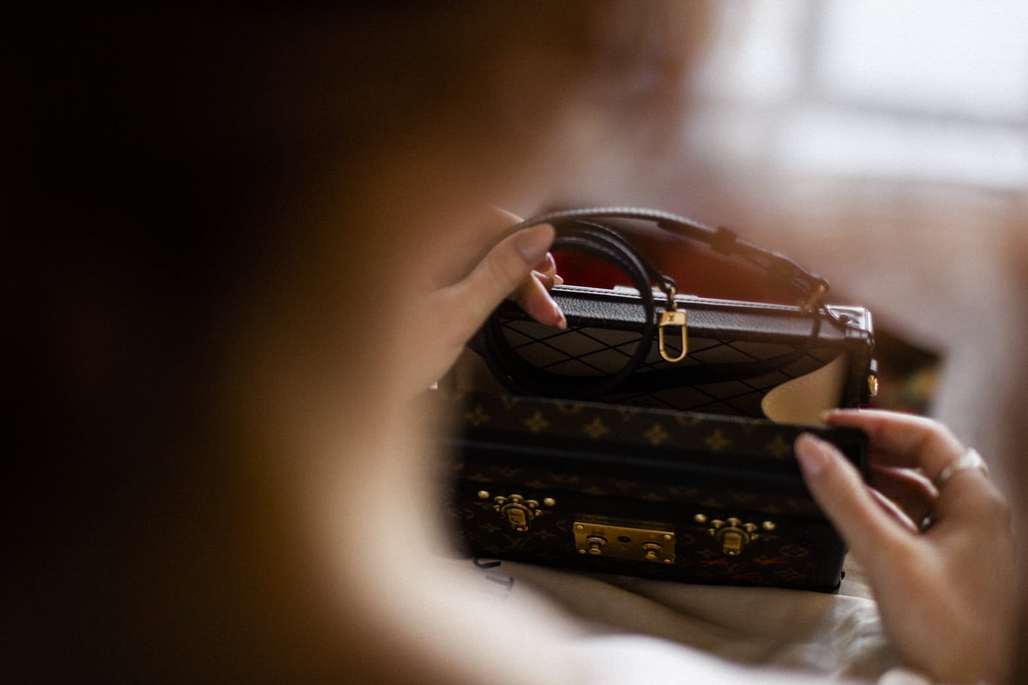 A close-up of a person's hand holding a luxury handbag with intricate details and a luxurious design.